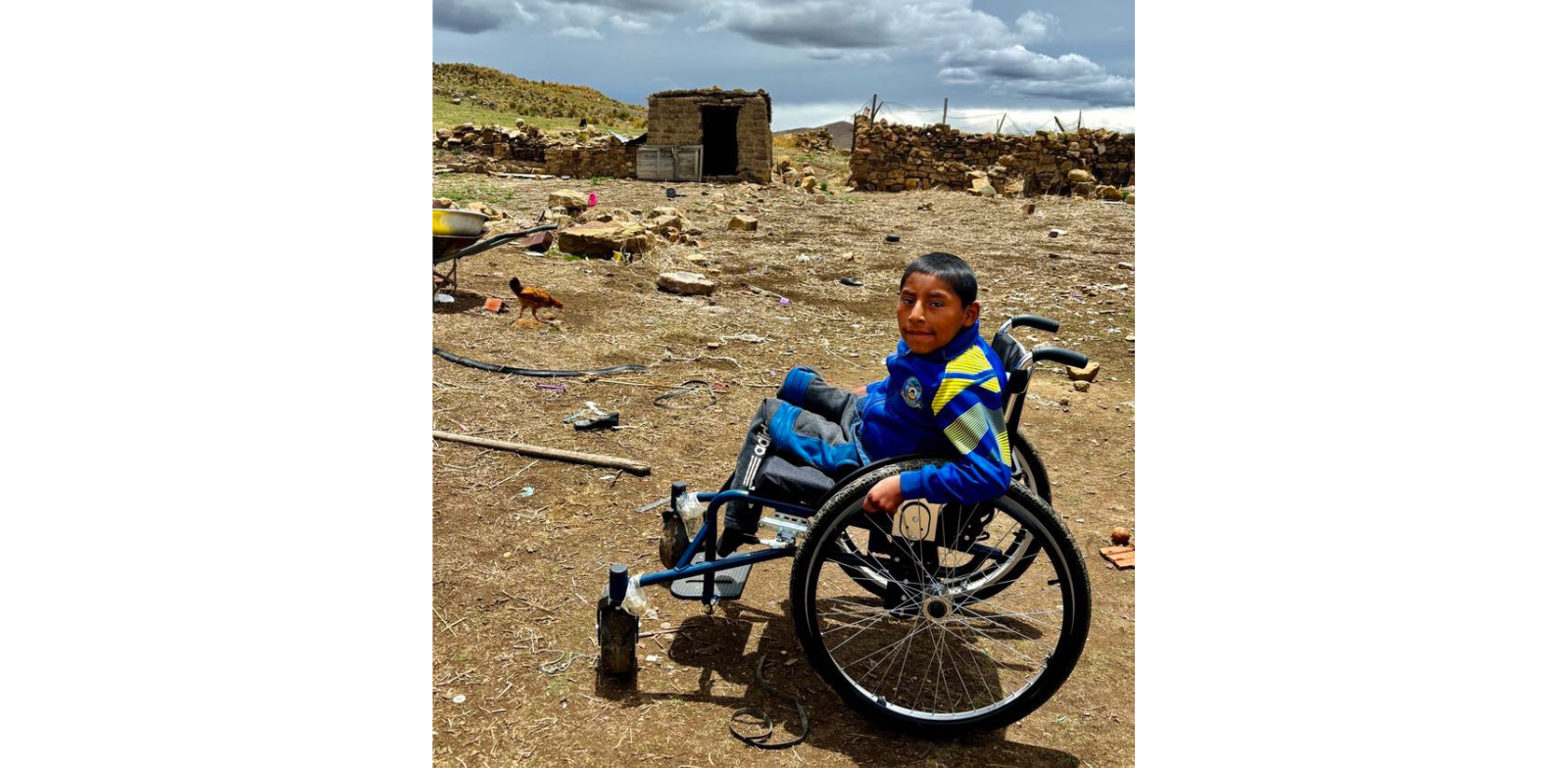 Jhon devant son terrain sur sa chaise adaptée